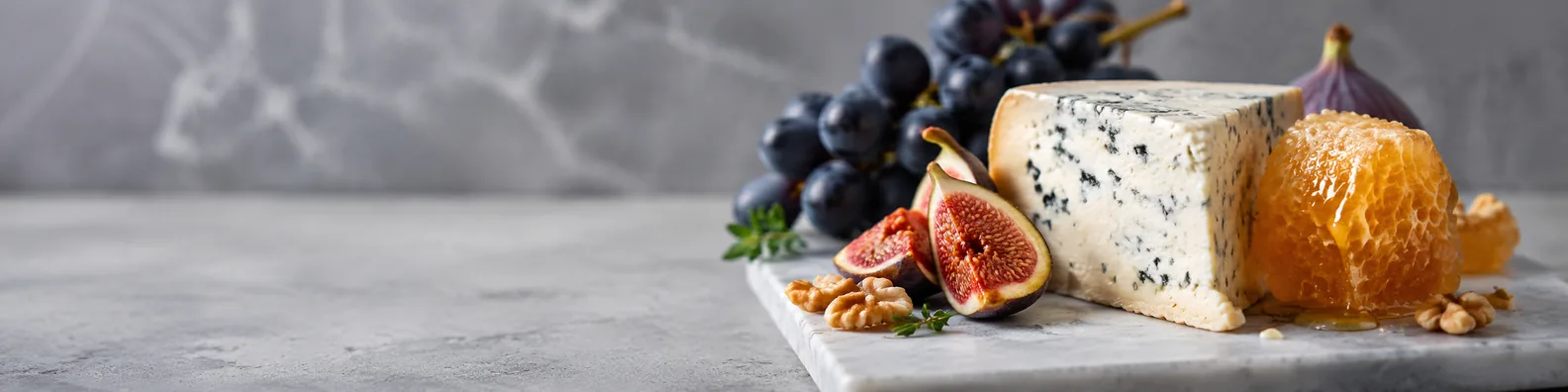 Premium styled food scene with cheese, figs, grapes, honeycomb, and walnuts LinkedIn background banner