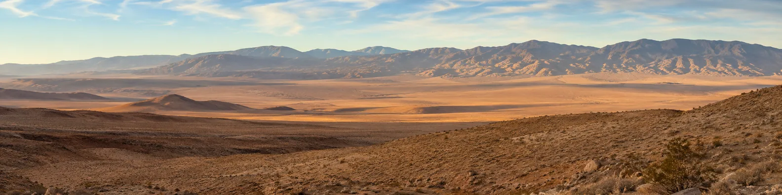 Desert mountains panorama LinkedIn background banner with wide desert land, distant rugged mountains, soft sunlight, and open sky