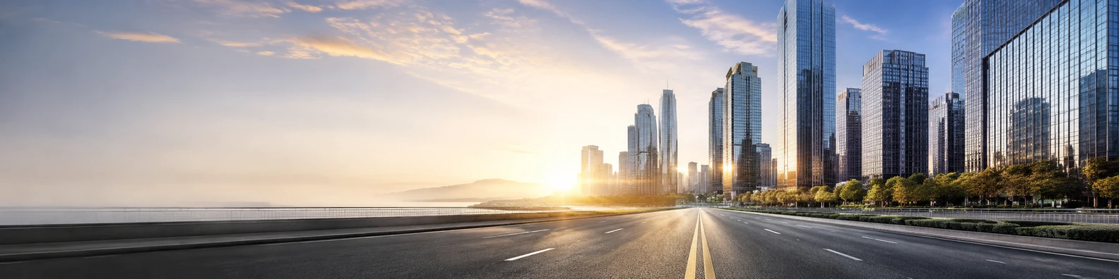 Downtown road perspective leading toward modern city skyline and warm sunset light LinkedIn banner