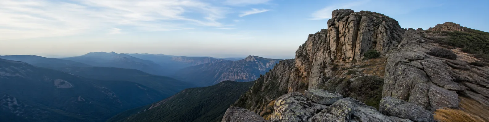 Rugged mountain rock cliffs with distant layered ranges and open sky LinkedIn background banner