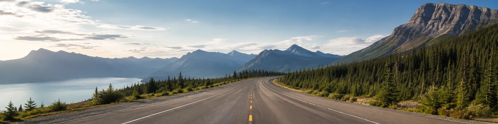 Open road leading through mountains and forest in bright natural light LinkedIn background banner
