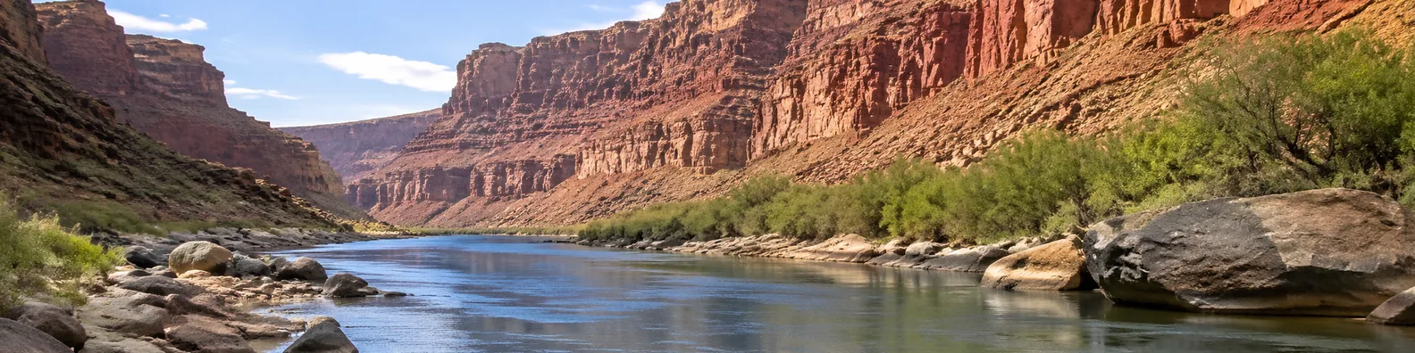 Rocky canyon river LinkedIn background banner with canyon walls, calm river, stones, warm sunlight, and natural desert landscape