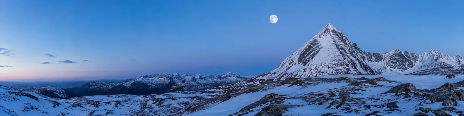Snow covered mountain peak under a rising moon in blue twilight LinkedIn background banner