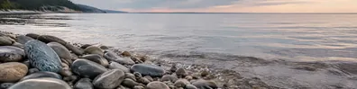 Smooth stones beside a calm shoreline with gentle water LinkedIn background banner