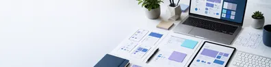 UX design technology desk LinkedIn background banner with wireframe papers, laptop interface layouts, sticky notes, pen, tablet, keyboard, and clean desk accessories